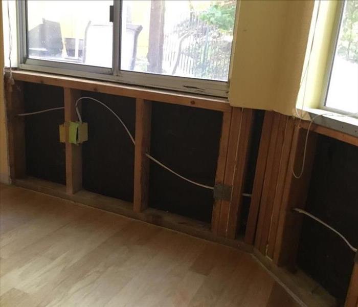 Image of same breakfast nook area with tables and chairs removed and flood cut in the wall done removing affected material.