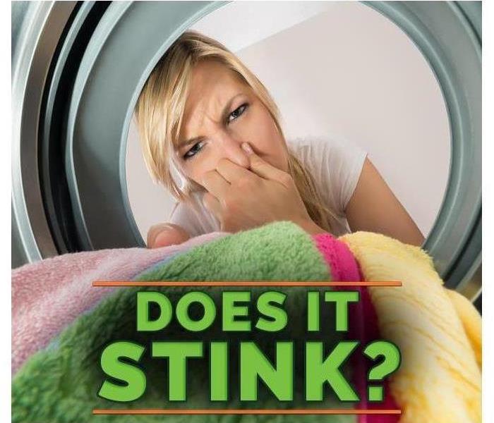 Woman looking into a washer and plugging her nose. Caption, "does it stink?" 